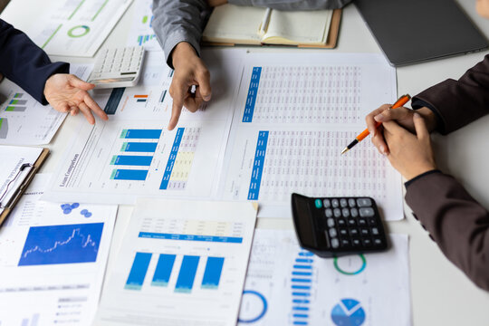 Business professionals discussing financial reports and charts during an office meeting, analyzing data for planning and strategy.