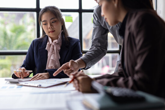 Business colleagues collaborating on data analysis, discussing market trends, and planning corporate strategy during a formal meeting.