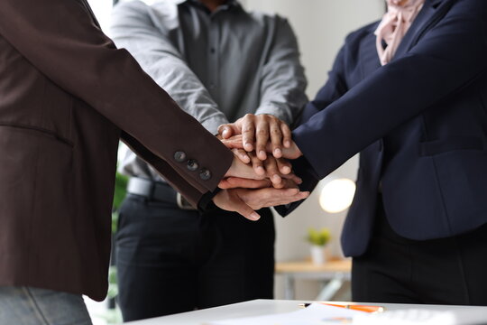 Business people stacking hands showing teamwork and collective effort.