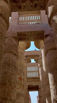 Karnak Temple in Luxor, Egypt. Massive hieroglyphic columns in Great Hypostyle Hall, Karnak Temple Luxor Egypt. Upward view of ancient carved pillars against blue sky.