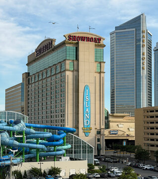 Vertical view of the showboat and hard rock resorts, multi-level parking garage, waterpark slides, busy streets and summer tourism under a clear sky.