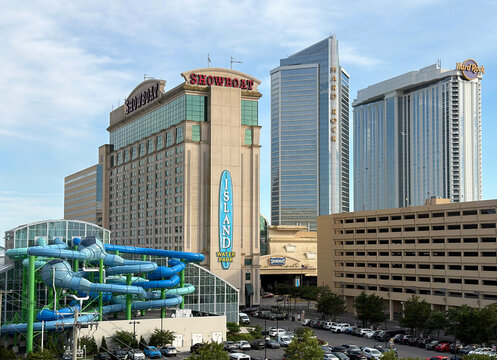 Horizontal view of the Showboat and Hard Rock resorts, multi-level parking garage, waterpark slides, busy streets and summer tourism under a clear sky.