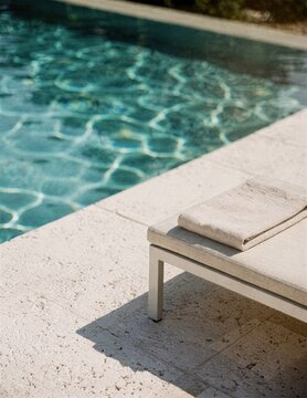 Minimal poolside lounge chair beside clear blue water on sunny terrace