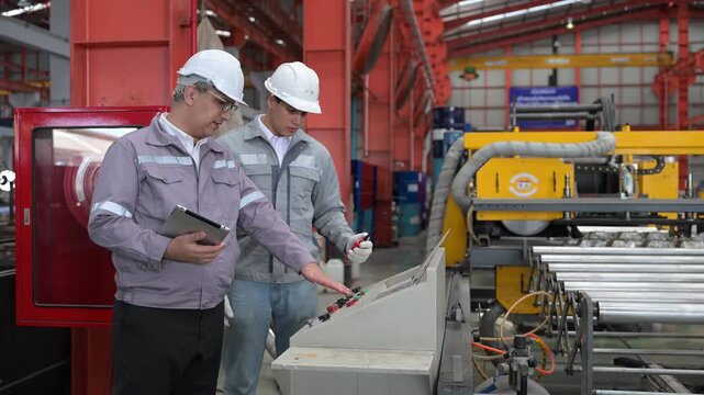 Two professional industrial engineers wearing safety helmets and uniforms pointing at the automation control panel interface while discussing plant operation parameters today.
