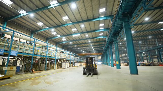 large factory inside, lifter moving inside the manufacturing plant. technical production factory. well lit production facility