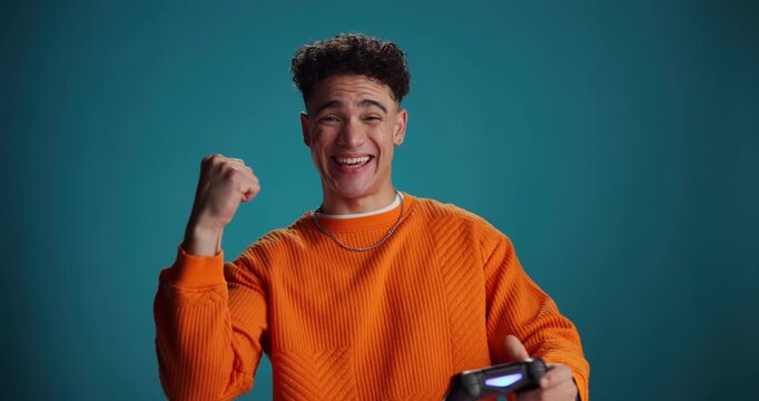 Video games, excited and face of man in studio for online competition, challenge and esports. Space, gamer and portrait of person with console remote for fun, playing and happy on blue background