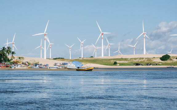 Multiple Wind Turbines Over Dunes with Anchored Boats and River in Northeast Brazil