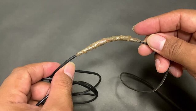 Hand repairing broken cable with tape. electricity maintenance.
