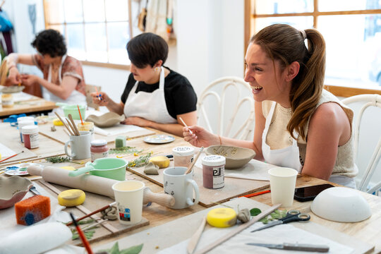Friends collaborating and creating unique ceramic pieces in a joyful art workshop