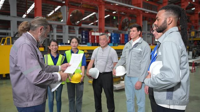 Factory workers reviewing workplace information together during a safety meeting in a manufacturing facility, supporting teamwork and operational efficiency.