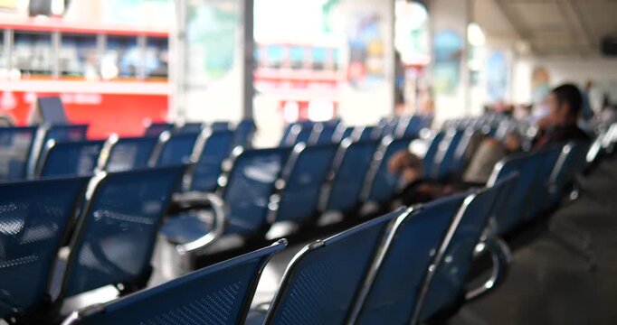 Rows of blue chairs in bus terminal with blurry buses background