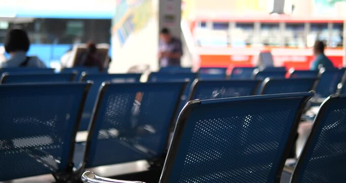 Rows of blue chairs in bus terminal with blurry buses background