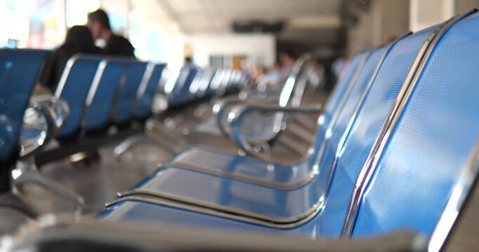 Rows of empty blue metal chairs in terminal waiting area