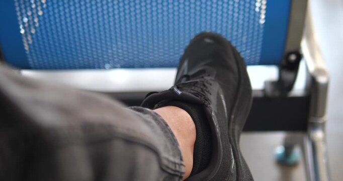 POV close up of man leg in black denim jeans sitting with crossed legs