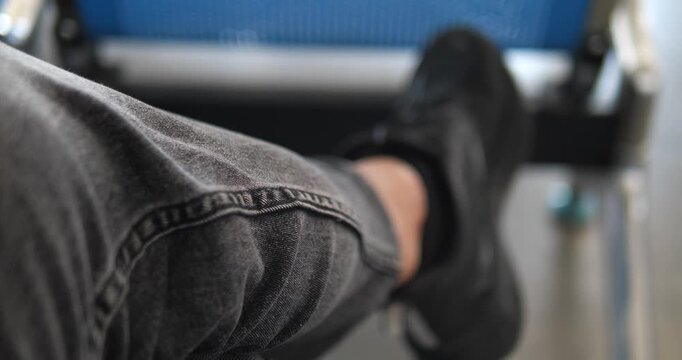 POV close up of man leg in black denim jeans sitting with crossed legs