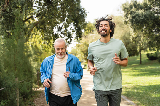 Senior dad man jogging doing sport together with his son, running for healthy lifestyle and family bonding