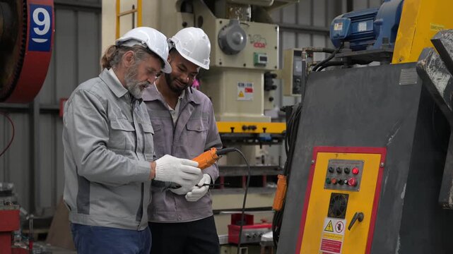 Engineers operating heavy machinery with handheld control panel