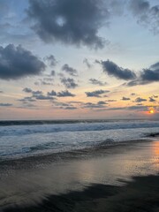 Fototapeta premium Dramatic ocean sunset with bright sun glowing at the horizon and reflecting on wet beach