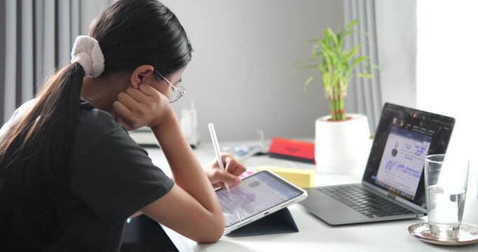 Rear view of young Asian woman thinking and working at desk