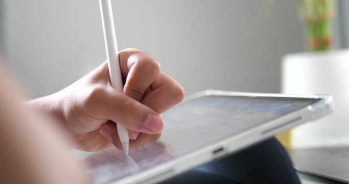 Close up hand using stylus pen writing on digital tablet screen