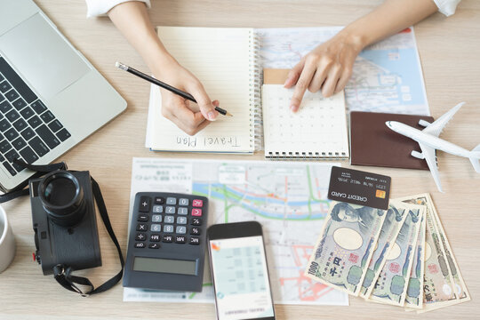 Travel planning, vacation, holiday trip concept, asian young tourist woman hand take note to check travel date on calendar and information for booking hotel online, ticket preparing for journey trip.