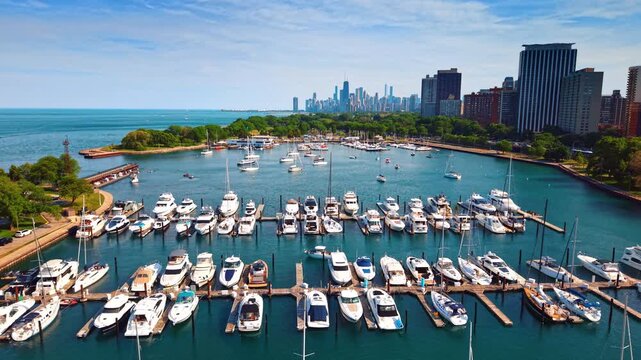 Monroe Harbor yacht slips with skyline in background, Chicago, Illinois. Rows of white yachts and sailboats berthed along piers with Lake Michigan and downtown towers beyond.