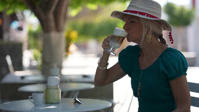 Senior woman sits at cafe near Loreto mission church enjoying coffee while taking in the sights and sounds of the area.