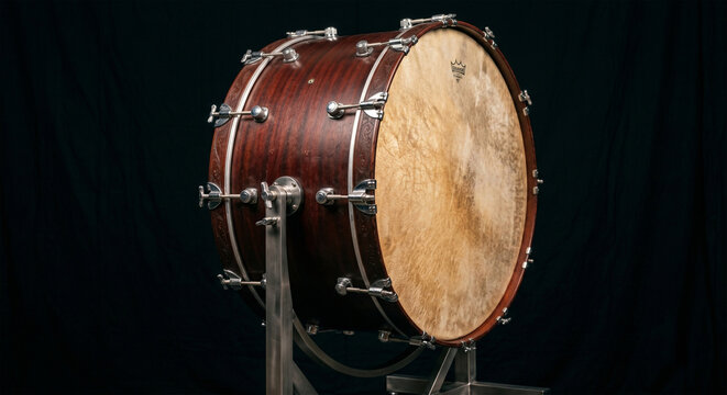 A professional product photograph of a modern concert bass drum suspended in a tilting cradle stand, positioned against a seamless, matte-black background 