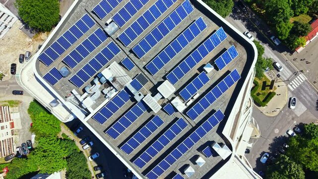 Solar panels are installed on a rooftop in a city. The panels gather sunlight for energy. Surrounding trees and streets can be seen. This setting highlights the use of renewable energy.