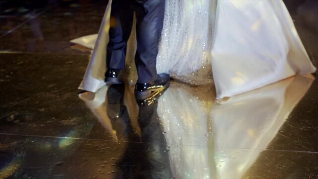 Shot of the feet of a bride and groom dancing their first dance at a wedding, on a floor of mirrors