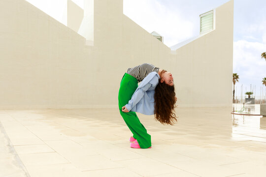 Woman Bends Back on a Rooftop During the Day in a Bright Outfit