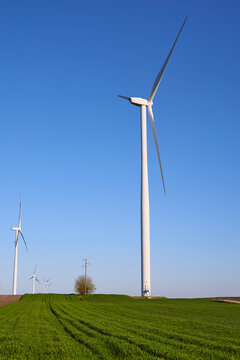 Wind turbines at sunset in green field &ndash; renewable energy, clean power, sustainable future.