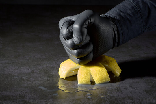 Hand in black glove smashing empty lemon peel concept of bankruptcy and asset exhaustion