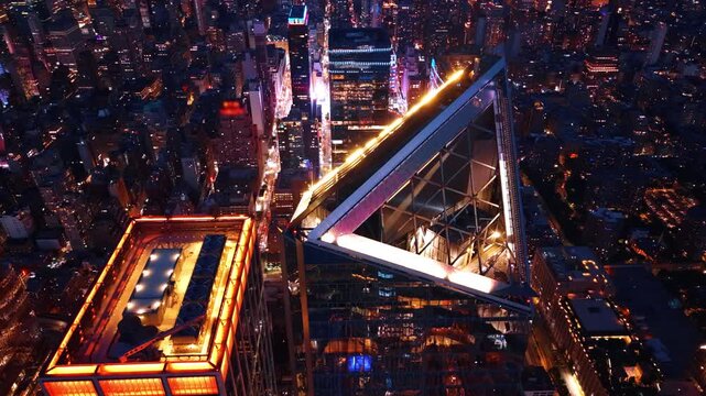 Architectural details of a triangular skyscraper roof, New York City. Illuminated glass peak of a modern tower surrounded by glowing midtown streets.