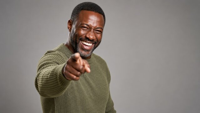 Happy laughing man pointing at camera with cheerful expression friendly positive portrait on neutral background