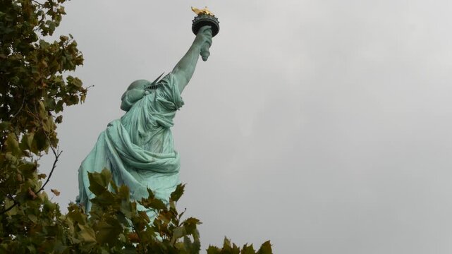 Statue of Liberty on Liberty Island, New York, United States. Cooper monument, symbol of democracy and patriotism near Manhattan, NYC USA. American independence. Autumn fall leaves. From behind, back.