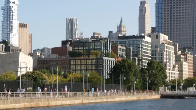 New York City Manhattan downtown financial district skyline, United States. Urban waterfront cityscape, World Trade Center skyscraper building, Hudson River Park, people walk on riverfront promenade.