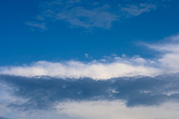 Fototapeta premium Picturesque view of a changing summer sky with dense white and dark cumulus clouds. Contrasting layers of cloud cover create a dynamic atmosphere above the horizon on a fine day. Beautiful natural bac