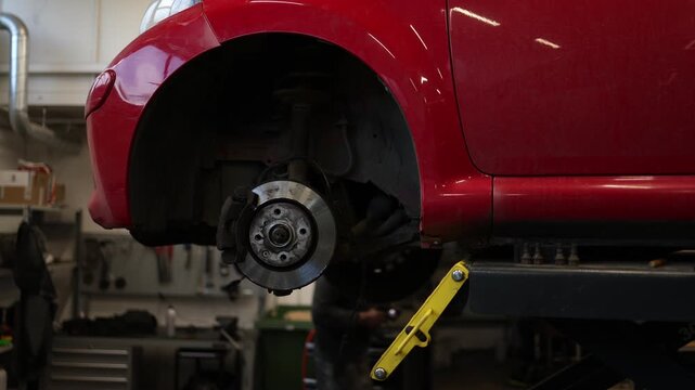 vehicle on a hydraulic lift with a wheel removed during repair work showcasing automotive maintenance mechanical service and professional diagnostics