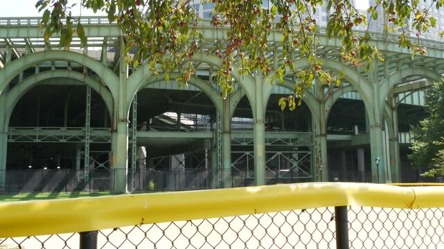 New York City, Manhattan, United States of America. Riverside Park South. Miller highway remnant, elevated viaduct in Upper West Side. Green arch of overpass bridge ruins near baseball sport field.