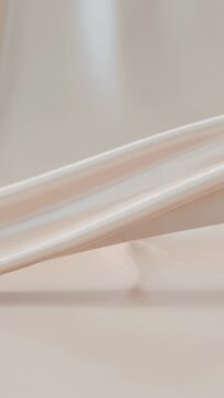 Vertical video: Pinch forming, ivory satin fabric gliding across studio table, smoothing hem