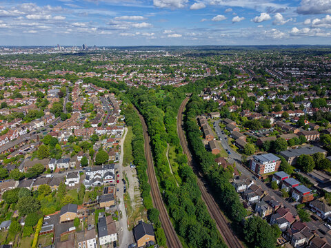 Aerial view of Y shape railway tracks in Sutton, Greater London, UK. Above residential area on a sunny day with blue sky. Croydon modern skyline in background. Green public park between railway tracks