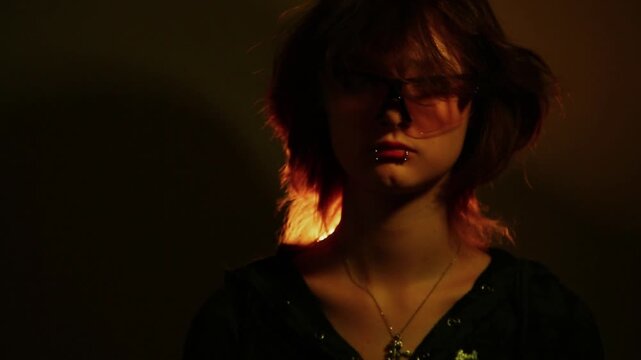 Portrait of a young woman posing in studio creative light in protective sport fashion sunglasses. Expression girl face with piercing on lips. Closeup art moving