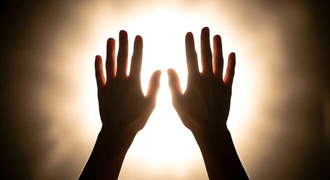 Human hands reaching up toward bright warm light representing hope and faith