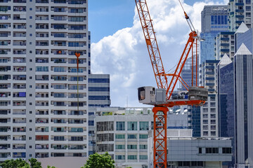 Tower crane operating among modern residential and commercial high-rise buildings in Thailand. Urban development, real estate growth. © All times 