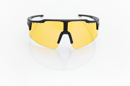 stylish sunglasses on a glossy white table, yellow glass, black sunglasses frame, yachting glasses, cycling glasses, reflection on a glossy surface