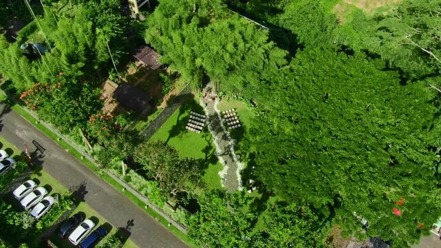 Aerial shot of luxury hotel surrounded by tall green trees or rainforest and rice field in Ubud, Bali