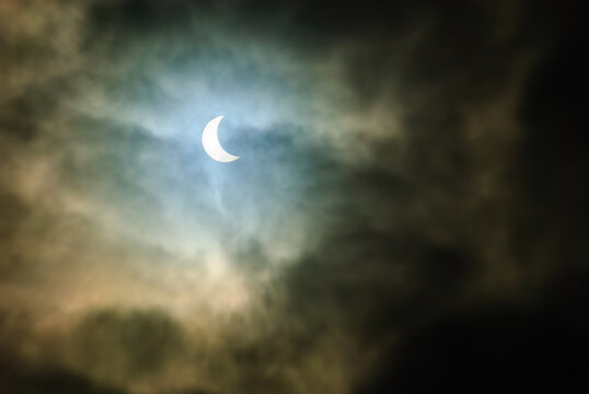 Partial solar eclipse seen through dramatic clouds