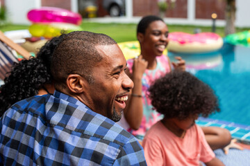 Fototapeta premium Group of people laughing by a pool with colorful inflatables.