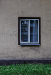 Fototapeta premium the wall of an old house with a window and green grass